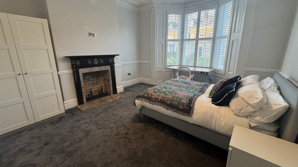 Bedroom with bay-window desk, period fireplace and double bed at 61 Bishopthorpe Road